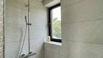 Une salle de bain avec une douche, une fenêtre et un distributeur de serviettes.