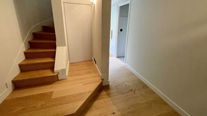 A wooden staircase with white walls and a carpeted floor.