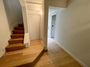 Un escalier en bois, avec des murs blancs et un sol recouvert d’une moquette.