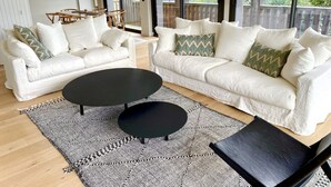 A spacious living room with two white sofas, a black coffee table, and a patterned rug.