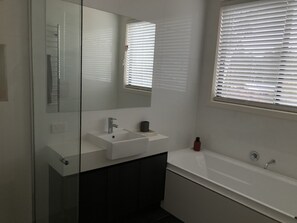 A modern bathroom with a glass shower enclosure, a white sink, a mirror, and a window with blinds. - Unique modern, spacious, clean large 3 bedroom + study  in beautiful Blackwood (Blackwood)