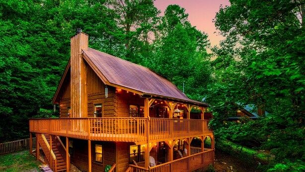 Eine Holzhütte mit Balkon, umgeben von dichtem Wald.