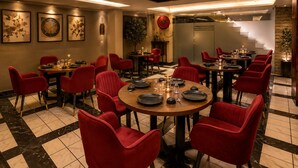 Un restaurante con mesas redondas, sillas rojas y suelo de cuadros.