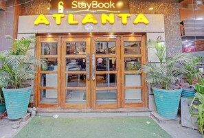 Entrada de hotel StayBook ATLANTA con puertas de madera y grandes macetas.