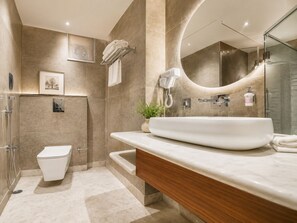 Un baño moderno con un lavamanos grande, inodoro, ducha y espejo.
