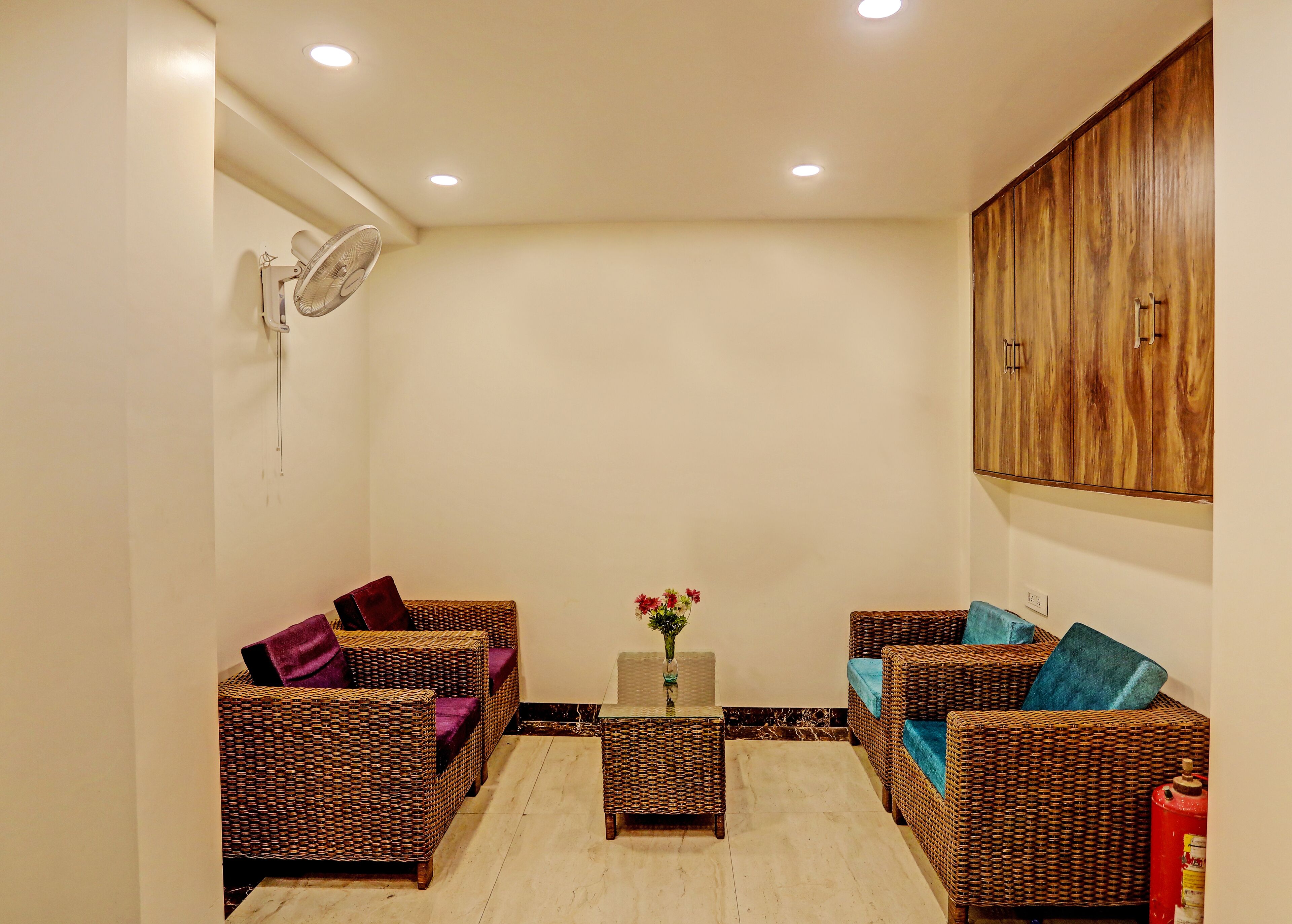 A room with wicker furniture, a small table with a vase, and a wooden cabinet.