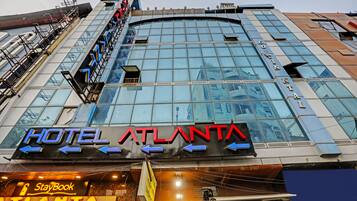 A hotel with a large glass facade, signage for 'Hotel Atlanta', and a 'StayBook' sign below.