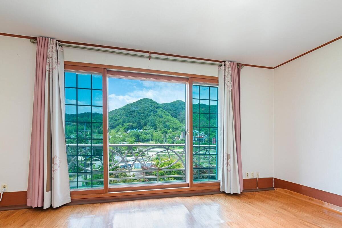 Une pièce dotée d’une grande porte-fenêtre coulissante donnant sur un balcon avec vue sur les montagnes.