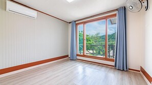 A room with a large sliding glass door to a balcony, a ceiling fan, and a white air conditioning unit. - Gangchon Chocolate World Pension (Chuncheon)