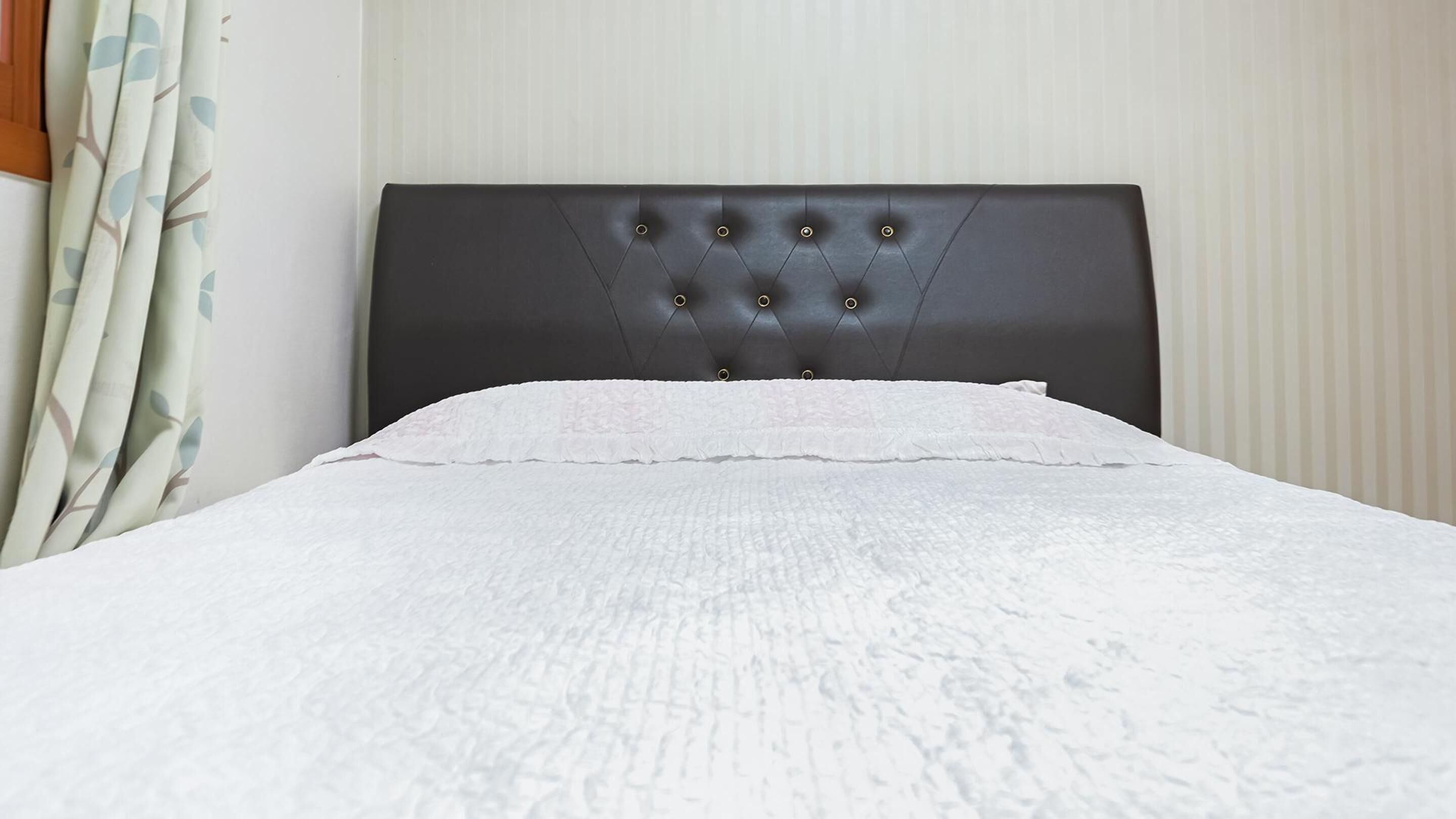 A bed with a tufted headboard and a white textured bedspread.