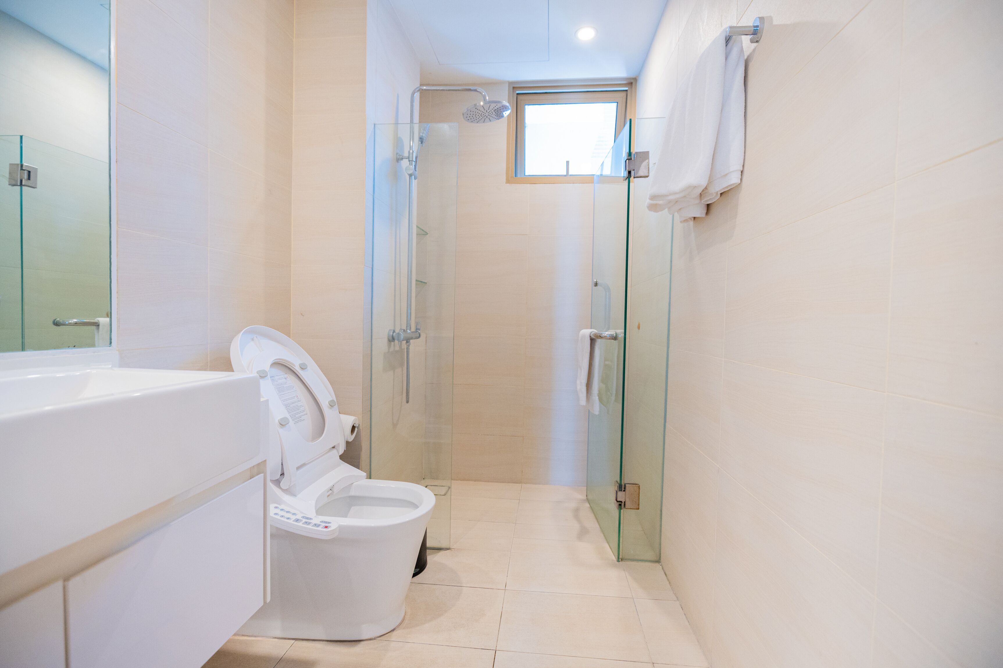 A modern bathroom with a glass-enclosed shower, a toilet with a control panel, and a bathtub.