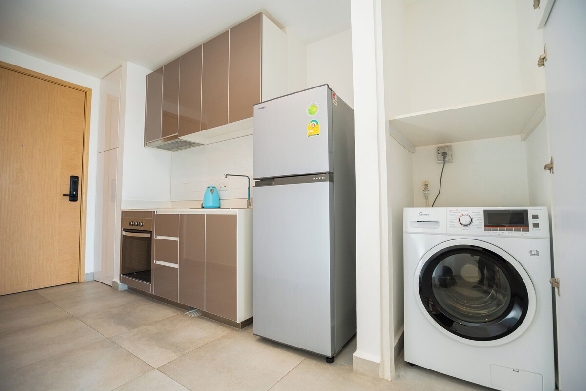 Una cocina funcional con refrigerador, horno y lavadora.