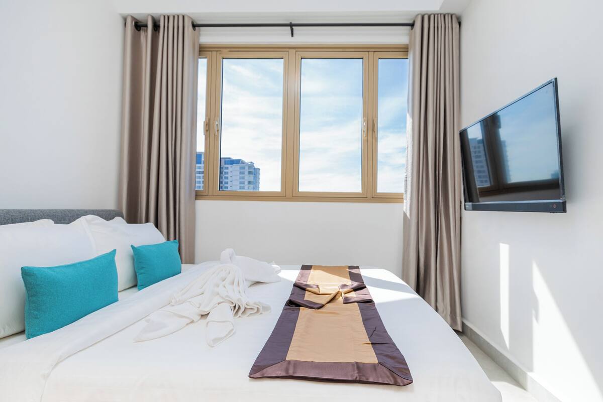 Ein Hotelzimmer mit Bett, Fernseher und einem Vorhangfenster.