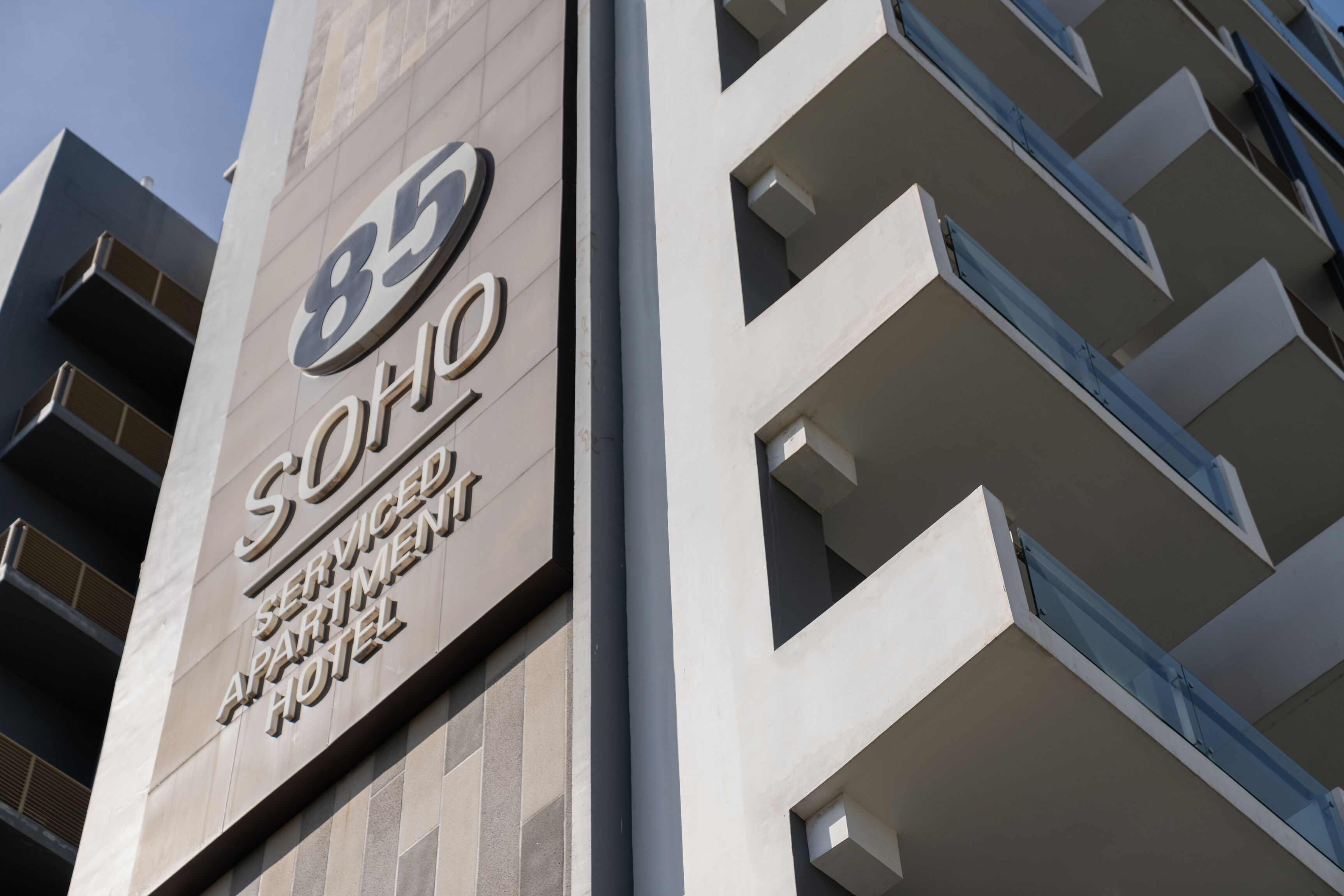 Un edificio moderno con un cartello che riporta la scritta "85 Serviced Apartment Hotel".