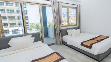 A hotel room with two beds, large windows, and a view of buildings.