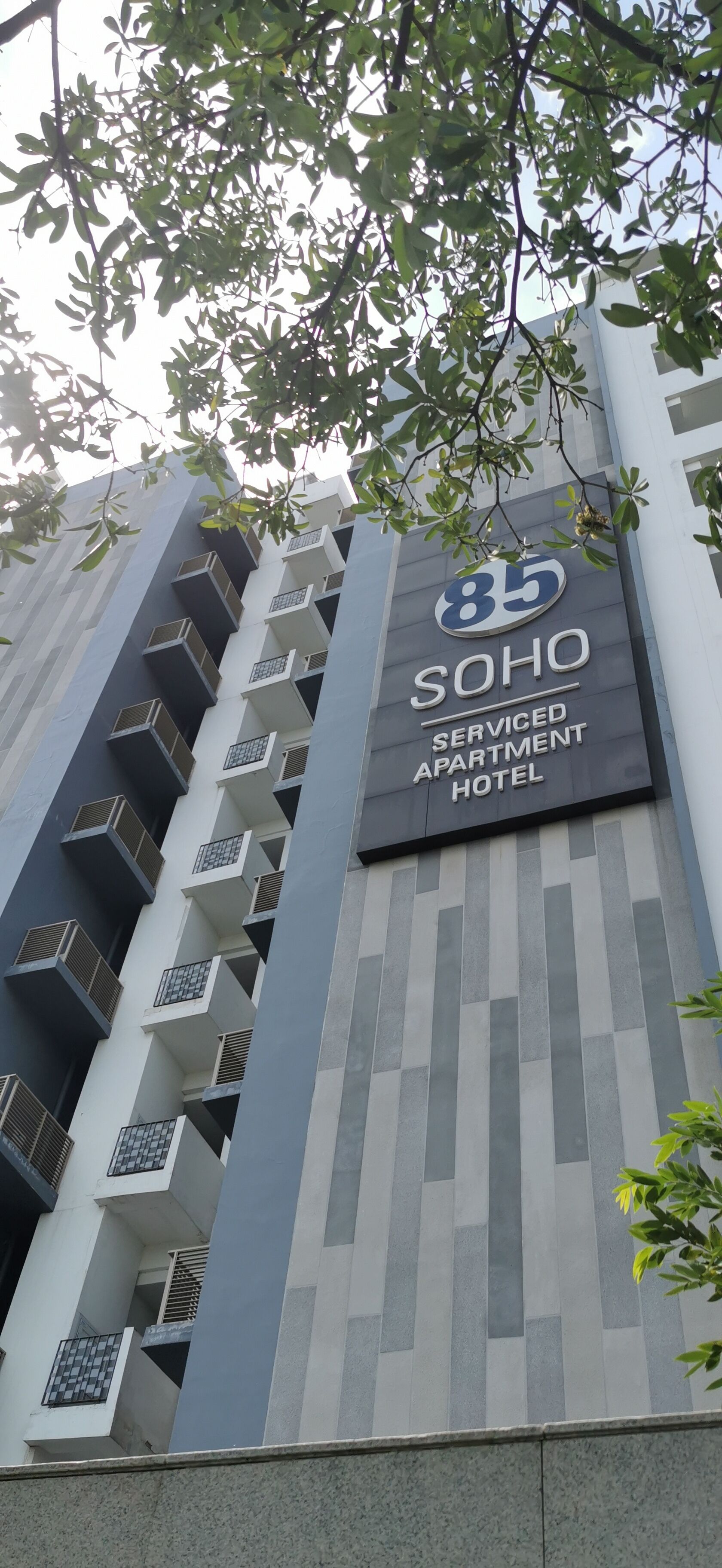 Un hotel-apartahotel con diseño moderno, que destaca un cartel con el número 85 y el nombre 'SOHO'.
