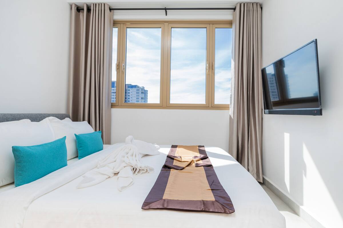 Ein Hotelzimmer mit Bett, Fernseher und einem Vorhangfenster.