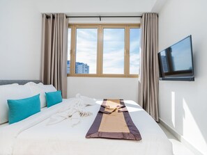 Une chambre d’hôtel avec un lit, une télévision et une fenêtre avec des rideaux.