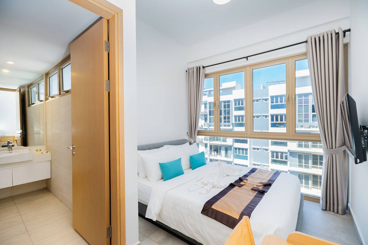 Ein Hotelzimmer mit Bett, Bad und großem Fenster mit Vorhängen.