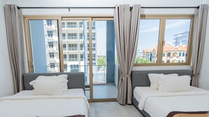 Una habitación de hotel con dos camas, un balcón y vistas a edificios.