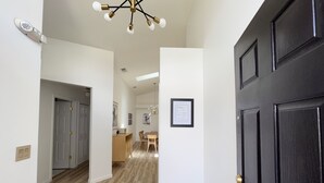 A modern interior with a dark wooden door, a hallway leading to a dining area, and a ceiling light fixture. - New Private Pool Mid Century Modern Home Near Disney Park (Kissimmee)