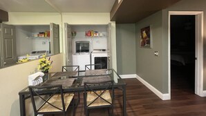 A dining area with a glass table and chairs, a kitchen with appliances, and a hallway leading to a bedroom. - Super Clean and Quiet Luxury Condo on the 2nd Floor (Las Vegas)