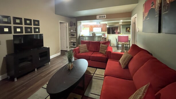 A living room with a red sofa, a TV, and a ceiling fan. - Super Clean and Quiet Luxury Condo on the 2nd Floor (Las Vegas)