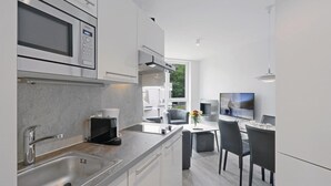 Una cocina moderna con microondas integrado, cafetera y zona de comedor con televisor.