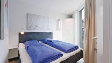 A modern bedroom with a bed, a headboard, a wall-mounted artwork, and a wardrobe.