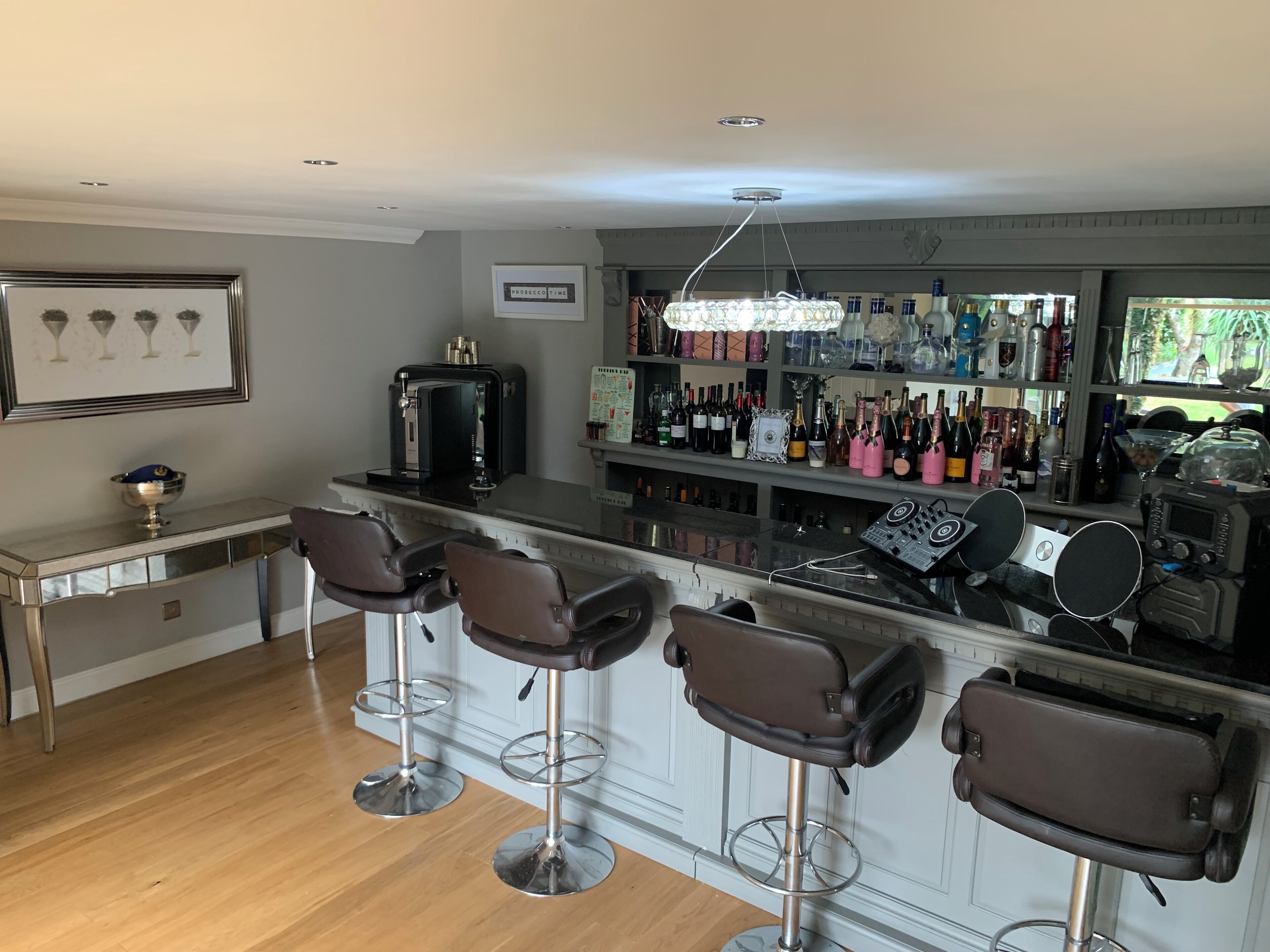 Un espace bar avec un comptoir, des tabourets et une variété de bouteilles et de verres.