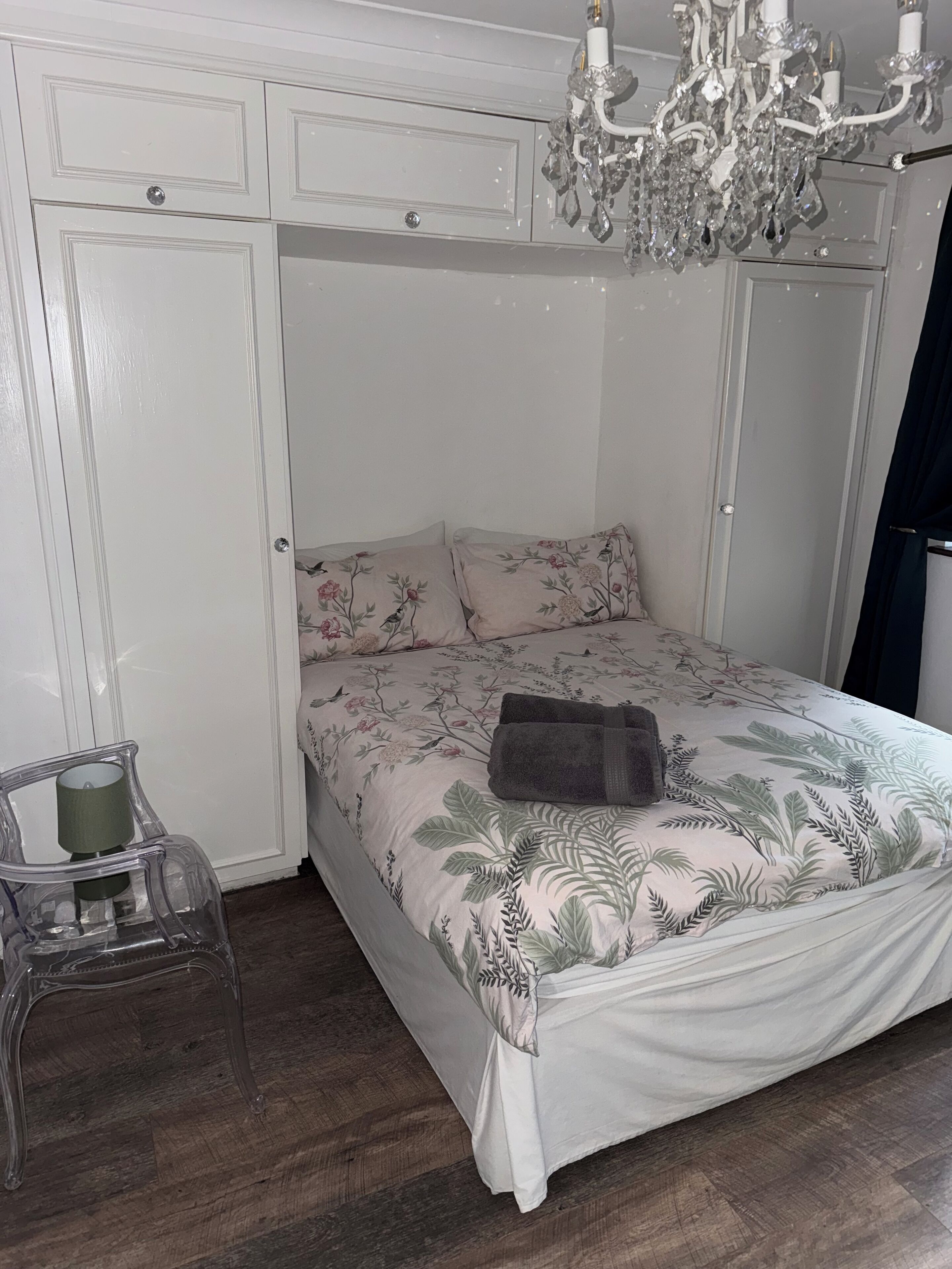Ein Schlafzimmer mit einem Bett, einer Chandelierleuchtre und einem Sessel.