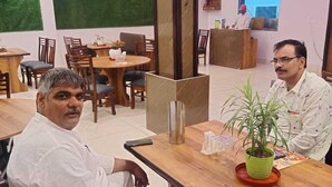A restaurant with wooden tables and chairs, a reception desk, and a clock on the wall. - Udiksh Hotel and Restaurants (Rohtak)