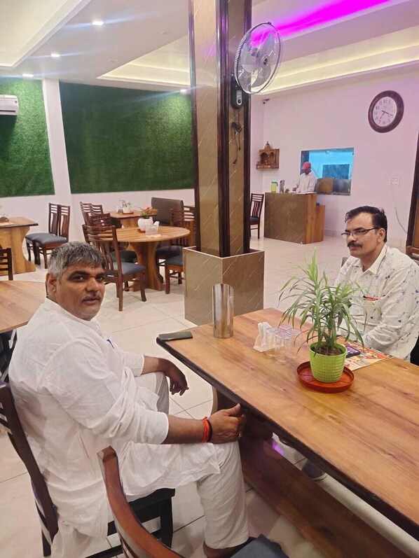 Un restaurante con mesas y sillas de madera, una recepción y un reloj en la pared.