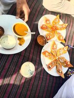 A table with food and drinks, including a bowl of soup, plates of stuffed flatbread, and small bowls of condiments.