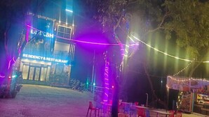 A nighttime outdoor area with a restaurant named "LUSH" and a seating area with chairs and tables. - Udiksh Hotel and Restaurants (Rohtak)