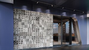A modern building facade with a geometric metal mesh design and a glass entrance. - Royal Group Hotel  Xiong Zhong  Branch (Kaohsiung)