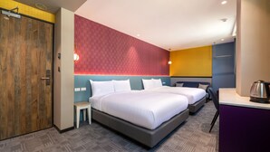 A hotel room with two beds, a wooden door, a red geometric wall, and a small table with a kettle. - Royal Group Hotel  Xiong Zhong  Branch (Kaohsiung)