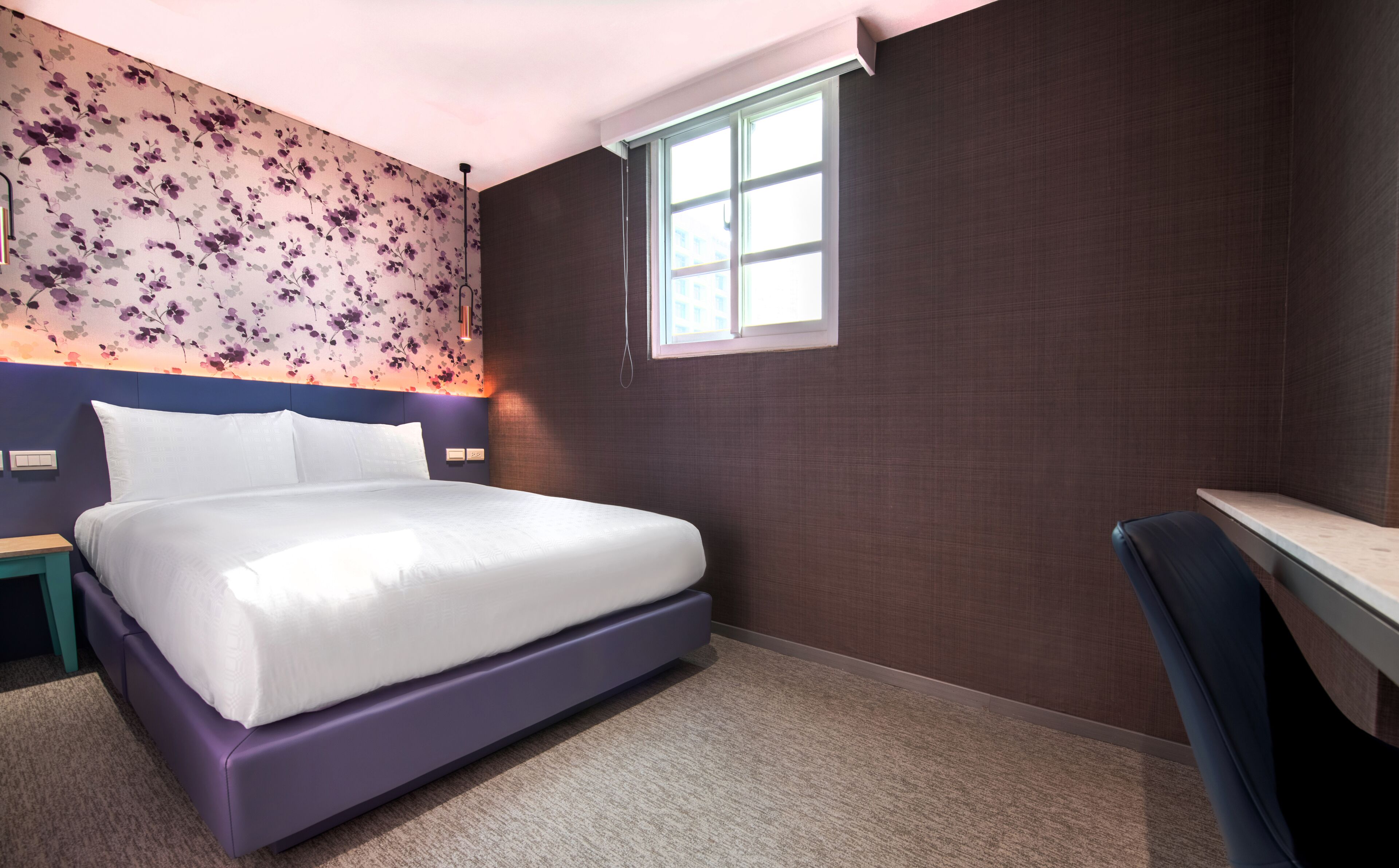 A modern hotel room with a large bed, a desk, and a window.
