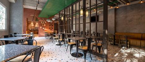 Interior de restaurante con mesas, sillas y piso de terrazo.