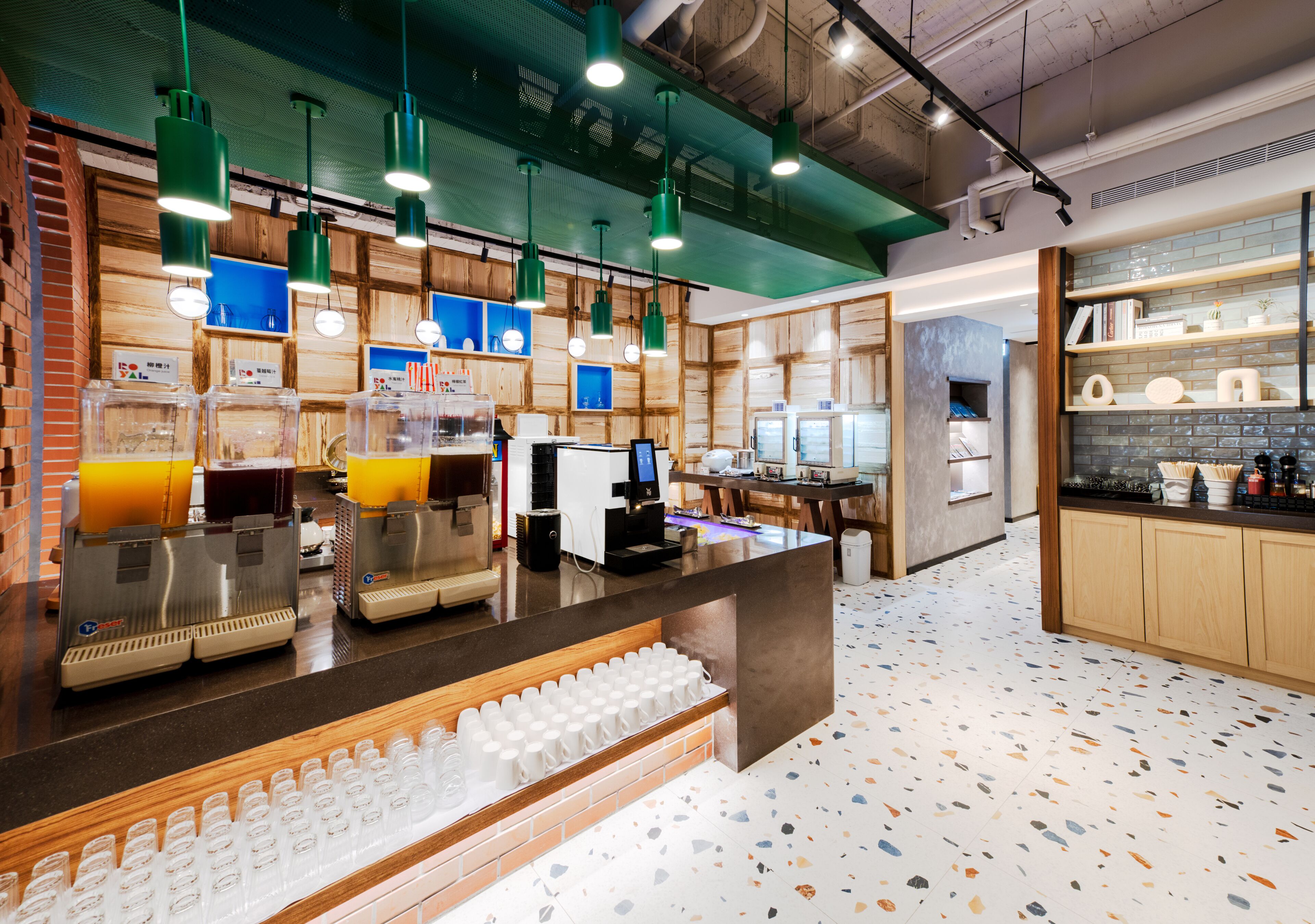 Una cafetería moderna con mostrador, máquinas de café y zona de estar.