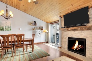Cozy living room with a fireplace, dining table, and flat-screen TV.