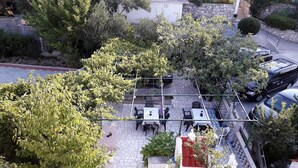 Un espacio al aire libre con mesas y sillas, rodeado de árboles y un muro de piedra.