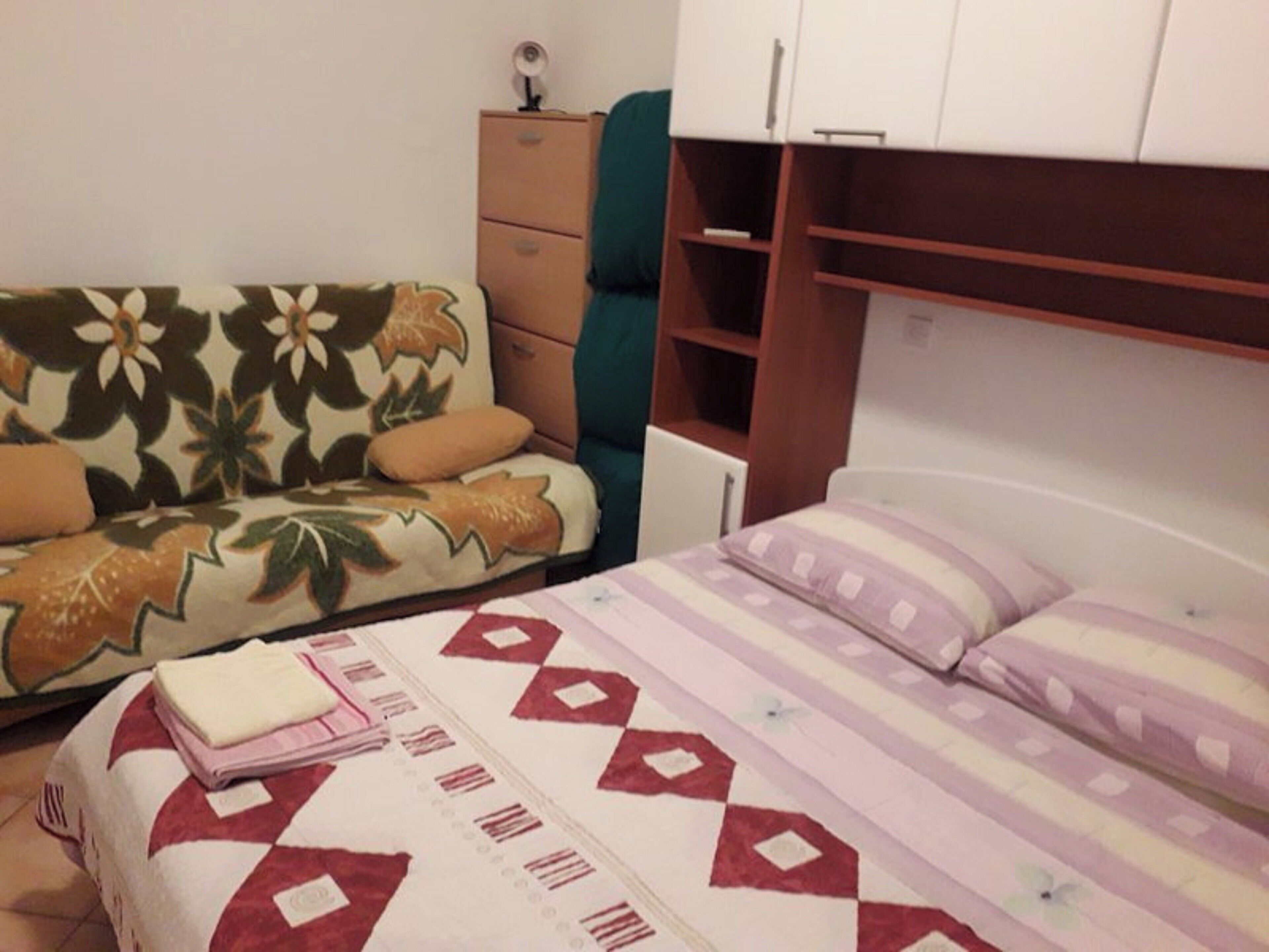 A bedroom with a bed, a sofa, a dresser, and a wardrobe.
