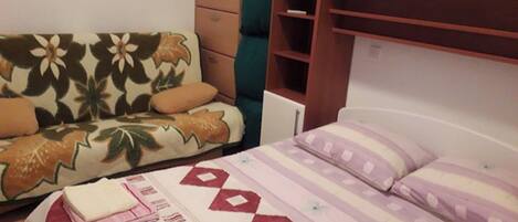 A bedroom with a bed, a sofa, a dresser, and a wardrobe.