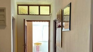 Un pasillo con una puerta de madera, una silla y cuadros en la pared.