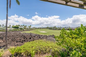 Un parcours de golf avec un ciel dégagé, des palmiers et une pergola en bois.