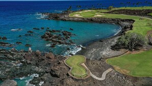 Ein Küsten-Golfplatz mit felsiger Uferlinie, klarem blauen Wasser und weiter Aussicht auf den Ozean.