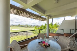Un balcon avec une table dressée pour deux personnes, donnant sur un terrain de golf.