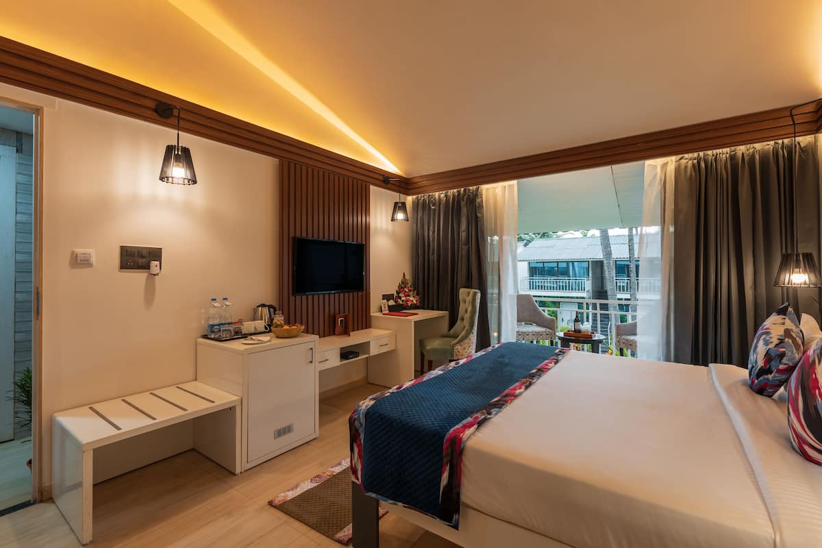 Quarto de hotel com cama, escrivaninha, televisão e varanda com vista.