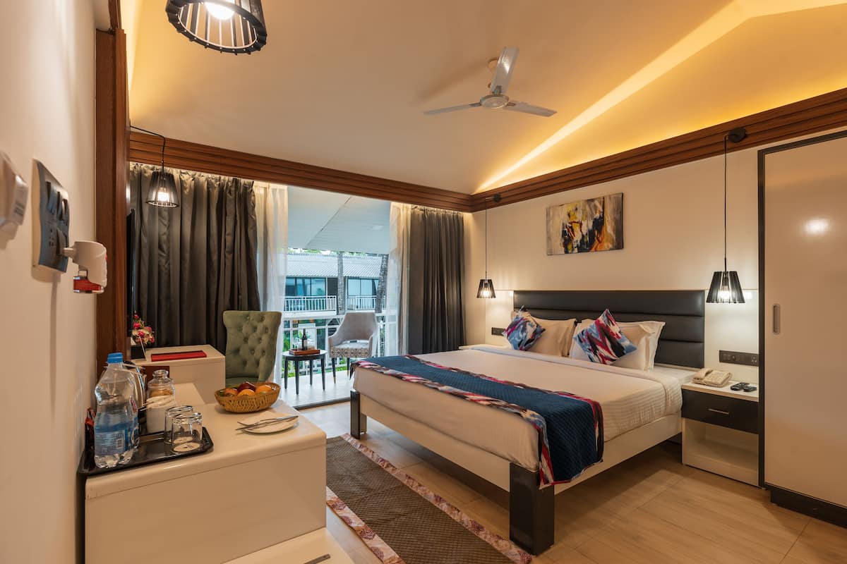 Quarto de hotel com cama, mesa de cabeceira, abajur e vista para o exterior.